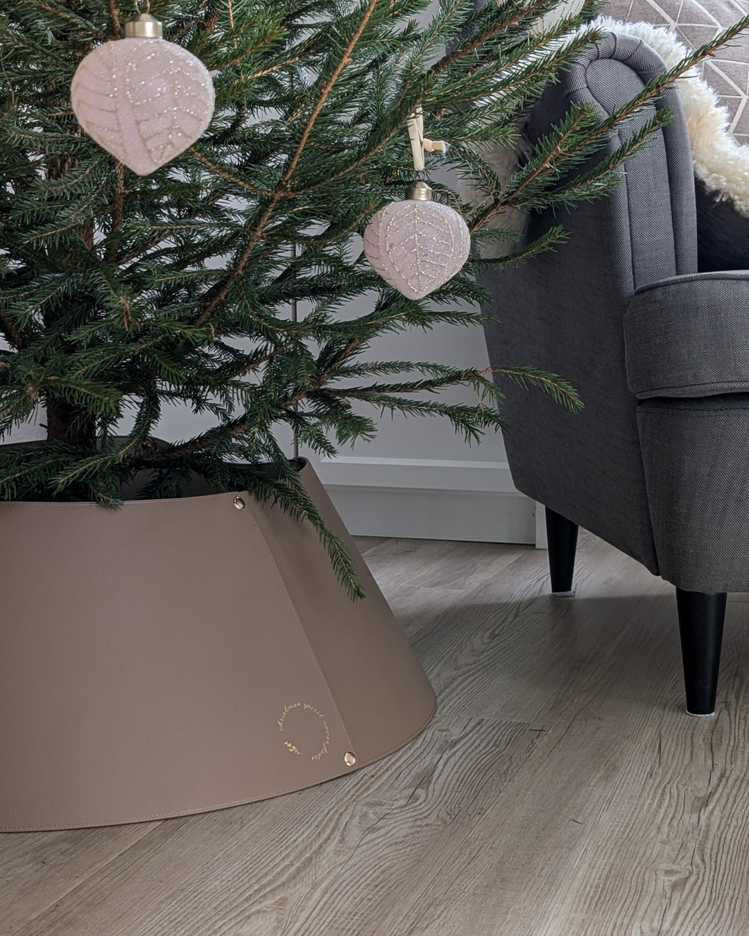 LIVLIG Christmas tree stand cover set up. Brown stand cover under a decorated Christmas tree